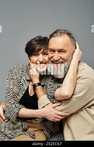 Una coppia di mezza età in un abbigliamento elegante che si abbraccia strettamente, mostrando amore e vicinanza in un ambiente studio. Foto Stock