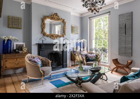 Antico specchio con cornice dorata sopra il caminetto con poltrone beige nella residenza georgiana Paultons Square, Chelsea, Londra, Regno Unito. Foto Stock