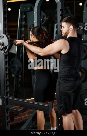 Un personal trainer assiste una sportiva bruna durante una sessione di allenamento in una palestra dotata di attrezzature fitness. Foto Stock