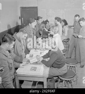 US ARMY UNIVERSITY, SHRIVENHAM, INGHILTERRA, Regno Unito, 1945 - le donne britanniche consigliano agli studenti della US Army University, Shrivenham, su varie questioni. Tra i GIS in cerca di consigli ci sono il caporale Wilfred Hoenninger, in primo piano, che viene mostrato un opuscolo sulla città di Cambridge da Meredydd Saunders-Davies. Il prossimo in fila (allontanandosi dalla telecamera) è il capitano Edward K Austin, che desidera andare in Scozia. Secondo la didascalia originale, "Diana Phipps dai capelli scuri appollaiata sullo sgabello in sottofondo è una nipote della duchessa di Gloucester". In primo piano, un'altra gi guarda una pila di copie della ' Foto Stock