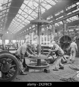 I lavoratori di un'officina di locomotive in Gran Bretagna montano i centri ruota in pneumatici caldi, utilizzando il restringimento mentre si raffreddano per fissare le ruote durante la produzione di locomotive ferroviarie nel 1945. Foto Stock