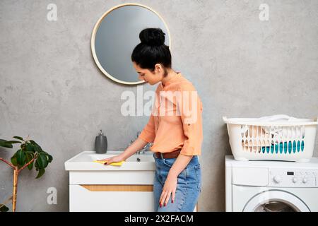 Una donna elegante in un abbigliamento casual davanti a una lavatrice, pronta ad affrontare le faccende domestiche. Foto Stock