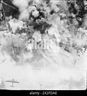 Una fotografia aerea verticale mostra un Avro Lancaster durante un raid alla luce del giorno da parte di 872 aerei della Royal Air Force sulle posizioni difensive tedesche vicino a Calais, mentre il fumo delle esplosioni oscura l'area bersaglio. Foto Stock