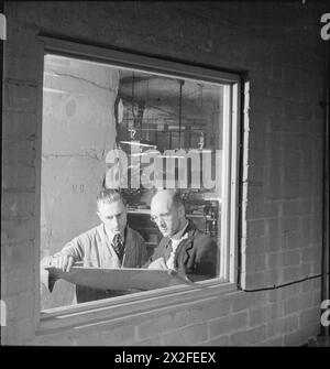 FABBRICA SOTTERRANEA: VITA QUOTIDIANA IN UNA FABBRICA SOTTERRANEA, PROBABILMENTE CAVA DI PRIMAVERA, CORSHAM, WILTSHIRE, INGHILTERRA, 1942 - il sovrintendente del negozio Charles Tunstall (a destra) dà istruzioni a un lavoratore sul lavoro giornaliero in questa fabbrica sotterranea Foto Stock