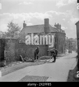 AMMINISTRAZIONE LOCALE IN Una CITTÀ DI CAMPAGNA: VITA QUOTIDIANA A WOTTON-UNDER-EDGE, GLOUCESTERSHIRE, INGHILTERRA, Regno Unito, 1944 - gli operai effettuano riparazioni su una strada a Wotton-under-Edge, Gloucestershire. Stanno ripavimentando e riparando la strada al sole. La didascalia originale afferma che il Consiglio della contea di Gloucestershire è responsabile di tutte le riparazioni e la manutenzione delle strade nel distretto rurale di Dursley, ma che le strade urbane sono mantenute dal Consiglio del distretto urbano. Il Consiglio della contea riceve una sovvenzione per il Ministero dei trasporti che varia dal 50% del costo sulle strade di classe 2 al 100% sulle arteri principali Foto Stock