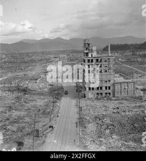 Una vista generale di Hiroshima dopo la bomba atomica del 1945, che mostra detriti, un edificio danneggiato del giornale Chugoku e un guscio distrutto di autobus o tram. Foto Stock