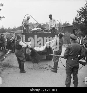 Le guardie del campo delle SS sono costrette a caricare prigionieri morti su un camion per la sepoltura nel campo di concentramento di Bergen-Belsen nell'aprile 1945. Foto Stock