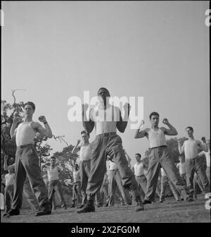 PRIMO CENTRO DI RIABILITAZIONE DELL'ESERCITO AMERICANO: RECUPERO E ADDESTRAMENTO PRESSO L'8° OSPEDALE CONVALESCENTE, STONELEIGH PARK, KENILWORTH, WARWICKSHIRE, REGNO UNITO, 1943 - il soldato David Brown (al centro) e gli altri suoi colleghi di classe B fanno 'salti stellari', ma con le braccia infilate, i pugni accanto alle spalle, durante una sessione di allenamento fisico all'8 ° Convalescent Hospital, Stoneleigh Park. Il soldato Brown (del 307 W. Holl Lanes, Savannah, Georgia) ha lavorato in uno stabilimento della Coca-Cola prima della guerra, e si sta riprendendo da un'operazione di ernia. Essendo un tirocinante di grado B, Brown è quasi tornato alla forma fisica completa: Una volta raggiunto il Livello Di g Foto Stock