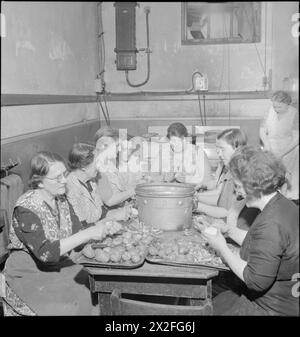 RISTORANTE WOOLMORE STREET: MANGIARE FUORI IN TEMPO DI GUERRA LONDRA, 1942 - le donne al lavoro preparano verdure nella cucina del British Restaurant a Woolmore Street. Da sinistra a destra sono: F Malyon (59 anni), C Pude (64 anni, operatrice di sigari in tempo di pace), Florence Skinner, Davison (una volta dimostrata la disponibilità di materiali per la pulizia), J Harrop (gestiva un negozio di mais e alimentari), Doris Prigge (precedentemente nel settore della ristorazione), Miss Barkwith, Miss Violet Hancock e Mrs Turley. Un'altra donna può essere vista sullo sfondo Foto Stock