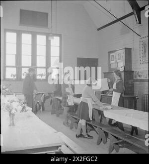 VILLAGE GARDENS DÀ DA MANGIARE AGLI SCOLARI: PRODUZIONE ALIMENTARE A KNIGHTON-ON-TEME, WORCESTERSHIRE, INGHILTERRA, Regno Unito, 1943 - dopo pranzo presso la scuola del villaggio di Knighton-on-Teme, la sala da pranzo viene ripulita e riportata al suo stato normale come aula. I ragazzi spostano le panchine e le scrivanie mentre le ragazze piegano i tovaglie Foto Stock