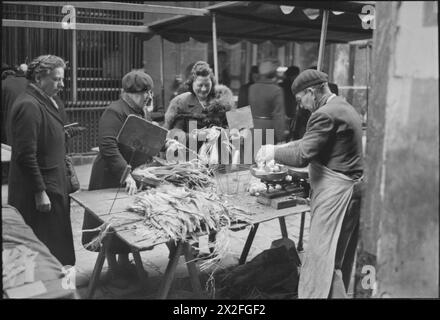 PARIGI, PRIMAVERA 1945: LA VITA DI TUTTI I GIORNI NELLA PARIGI LIBERATA, FRANCIA, 1945 - i civili francesi comprano patate e porri da un piccolo mercato, da qualche parte a Parigi. Secondo la didascalia originale "le patate sono razionate, la pila di porri non durerà a lungo, c'è molto poco altro da vendere" Foto Stock