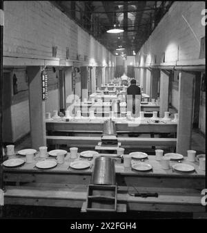 WAKEFIELD TRAINING PRISON AND CAMP: VITA QUOTIDIANA IN Una PRIGIONE BRITANNICA, WAKEFIELD, YORKSHIRE, INGHILTERRA, 1944 - Una vista di una delle sale da pranzo della Wakefield Training Prison. La prigione è costruita intorno alla sala centrale, con ogni ala dell'edificio conosciuta come "casa". Questa è la sala da pranzo di una delle case, allestita con tazze e piatti pronti per l'ora dei pasti Foto Stock