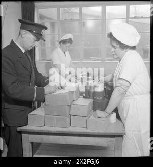 AEROPORTO DI PRESTWICK: TRASPORTO E VIAGGI IN TEMPO DI GUERRA, PRESTWICK, AYRSHIRE, SCOZIA, REGNO UNITO, 1944 - lo Steward Eldridge della stazione BOAC prepara le scatole per cena nelle cucine dell'aeroporto di Prestwick, mentre uno dei membri della cucina prepara le fiasche. Queste scatole sono per i 16 passeggeri e 5 membri dell'equipaggio che viaggiano quella sera. La didascalia originale afferma che in tempo di pace, il signor Eldridge ha servito pasti caldi in volo Foto Stock