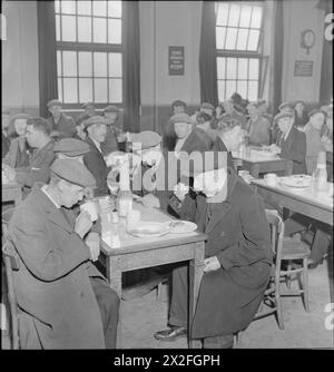 RISTORANTE WOOLMORE STREET: MANGIARE FUORI IN TEMPO DI GUERRA LONDRA, 1942 - i clienti possono gustare il loro pasto all'ora di pranzo al Woolmore Street British Restaurant a Poplar. In senso orario intorno al tavolo più vicino alla telecamera sono: 69 anni F Mann (un falegname), 53 anni J Hall (demolizione e recupero del ferro carman), 45 anni A Simmons (anch'egli impegnato nel recupero del ferro) e 77 anni T Hambly (servì come marinaio mercantile durante la prima guerra mondiale). Molti altri lavoratori possono essere visti ai tavoli sullo sfondo Foto Stock