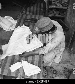 Gli artigiani nella città vecchia di Peshawar eseguono stampe a mano sui tessuti nel quartiere del bazar, dimostrando le tradizionali tecniche artigianali in un mercato commerciale. Foto Stock