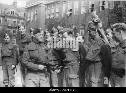 RISPOSTA: LA PRODUZIONE DI Un PROGRAMMA RADIOFONICO della BBC PER GLI STATI UNITI D'AMERICA, 1941 - poeta e radiofonico, Fusilier Z A Bokhari, è addestrato all'uso della pistola Tommy insieme ai suoi colleghi della BBC Home Guard, Bedford College. A Bokhari è stato dato un permesso speciale di indossare un turbante invece di un cappello da foraggio della Guardia Nazionale Foto Stock