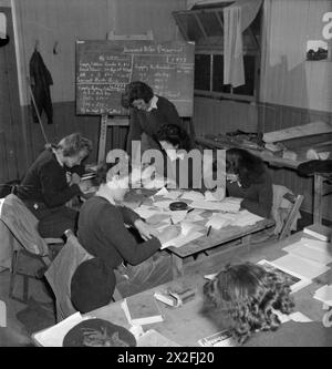 IMPARANO A ESSERE LUMBERJILLS: FORMAZIONE FORESTALE DELL'ESERCITO TERRESTRE FEMMINILE, CULFORD, SUFFOLK, 1943 - ragazze di terra specializzate in misurazione, calcolo dei costi e fatturazione, siedono un esame come parte della loro formazione a Culford. La lavagna fornisce esempi di avvisi sulla domanda Foto Stock