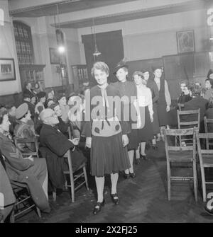 MEND AND MAKE DO: CORSI DI SARTORIA A LONDRA, 1943 - gli alunni di una classe di sartoria del London County Council tengono una sfilata di moda per mostrare ai loro amici e familiari ciò che hanno imparato. In primo piano c'e' la signora Johnson, che indossa il camice blu in cui era sposata 20 anni fa. L'abito è stato completamente ristrutturato con seta rosa e bianca. Dietro di lei, la signora Hill indossa una gonna fatta con un paio di pantaloni da postino. La terza in fila è la signora Bolton, della classe Kennington Foto Stock