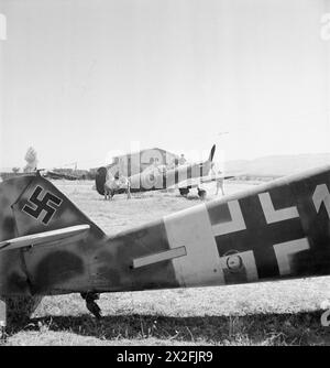 ROYAL AIR FORCE: ITALIA, BALCANI ED EUROPA SUDORIENTALE, 1942-1945. - Il Supermarine Spitfire Mark vs del No. 243 Squadron RAF è sottoposto a manutenzione a Comiso, Sicilia. Fotografato sopra la sezione di coda di un Messerschmitt Bf 109G abbandonato di 6/JG53 Royal Air Force, Sqdn, 243, German Air Force (terzo Reich) Foto Stock