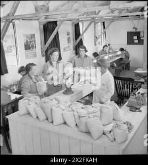 COMBATTONO ANCHE COLORO CHE SI LIMITANO AD ASPETTARE: LAVORO DI GUERRA PART-TIME NEL SURREY, INGHILTERRA, 1943 - al deposito di Chillingfold, la supervisore capo, signora Harner, pesa sacchi di rivetti dopo che sono stati ordinati da operaio di guerra part-time in varie "officine” della zona Foto Stock