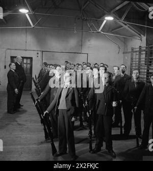 LONDON JEWS IN WARTIME: IL LAVORO DEI CLUB GIOVANILI DI STEPNEY, LONDRA, 1942 - Boy cadetti della Bernhard Baron Company, 1st Battalion Royal Fusiliers, City of London Cadets stanno all'attenzione, osservati dal loro comandante, il capitano Basil L Q Henriques JP, durante l'esercitazione del fucile nel ginnasio del Bernhard Baron Jewish Settlement in Berner Street Foto Stock