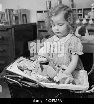LUSSEMBURGHESI IN INGHILTERRA: EVACUEES IN SURREY, 1942 - Jacqueline (3 anni) è un'evacuata dal Lussemburgo al Surrey. Qui la vediamo giocare con la sua bambola e la sua carrozza nella casa in cui risiede, da qualche parte nel Surrey Foto Stock