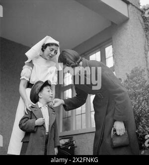 John Sutton di cinque anni indossa il cappello di suo padre mentre dice addio a sua madre al Flint Green Road Nursery di Birmingham, 1942. Un'infermiera lo guida all'interno mentre sua madre parte per lavorare in una mensa di fabbrica, illustrando il supporto per l'assistenza all'infanzia per le madri lavoratrici durante la seconda guerra mondiale Foto Stock