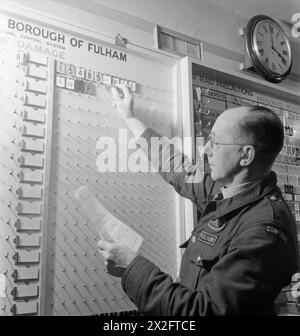 LA RICOSTRUZIONE DI "UN INCIDENTE": FORMAZIONE PER LA DIFESA CIVILE A FULHAM, LONDRA, 1942 - The Clerk-to-Officer-in-charge of the Control Centre inserisce le schede dal pannello di controllo al pannello degli incidenti. Queste schede rappresentano i servizi all'interno dell'incidente o in viaggio verso di esso Foto Stock