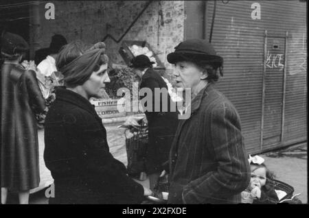 LA GRAN BRETAGNA FA LA FILA PER IL CIBO: RAZIONAMENTO E CARENZA DI CIBO IN TEMPO DI GUERRA, LONDRA, INGHILTERRA, Regno Unito, 1945 - due casalinghe discutono il problema della carenza di cibo durante un viaggio di shopping, da qualche parte a Londra Foto Stock