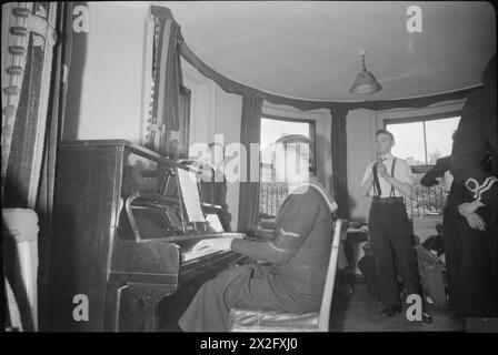 FESTA DI CONCERTI PACIFIC SHOWBOAT: PROVE DI MUSICA E DANZA DELLA ROYAL NAVY, LONDRA, INGHILTERRA, Regno Unito, 1945 - Un marinaio suona il piano durante una prova per il Pacific Showboat Concert Party, da qualche parte a Londra Foto Stock