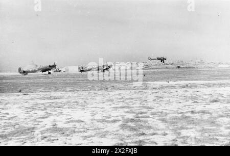 Tre Supermarine Spitfire Mark VC(T)S del No. 249 Squadron RAF aspettano presso la pista principale di Ta Kali, Malta, mentre un Bristol Beaufighter atterra durante le operazioni della Royal Air Force a Malta, Gibilterra, e nel Mediterraneo, 1940-1945. Foto Stock