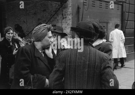 LA GRAN BRETAGNA FA LA FILA PER IL CIBO: RAZIONAMENTO E CARENZA DI CIBO IN TEMPO DI GUERRA, LONDRA, INGHILTERRA, Regno Unito, 1945 - Un gruppo di casalinghe discute il problema della carenza di cibo durante un viaggio di shopping, da qualche parte a Londra Foto Stock