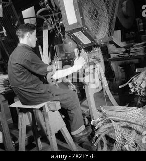 LETTERA IN PROIETTILE: TRASFORMARE LA CARTA RECUPERATA IN CARTUCCE DI FUCILE, INGHILTERRA, 1942 - questa fotografia mostra i resti delle strisce di cartone perforate mentre vengono gettate dalla perforatrice. Sulla sinistra della fotografia sono visibili solo le strisce di cartone prima che vengano inserite nella macchina Foto Stock