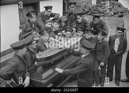 PRESSO L'ISTITUTO DI ADDESTRAMENTO DELLA MARINA MERCANTILE HMS GORDON. GIUGNO 1941, HMS GORDON, GRAVESEND. QUESTI UOMINI FIRMARONO PER IL SERVIZIO PRESSO LA ROYAL NAVY E GLI FU CHIESTO DI FARE VOLONTARIATO PER IL SERVIZIO MERCANTILE. - L'istruttore che spiega parti di una nave mercantile per mezzo di un modello alla sua classe Foto Stock