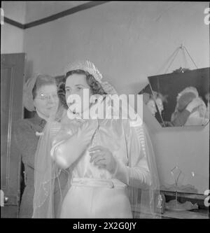 FOTO YMCA DA CASA: FOTOGRAFI CIVILI AL LAVORO, Regno Unito, 1944 - la fotografa amatoriale Miss Eveline Goist (di Birkenhead) aiuta la signora Hickman a regolare il suo velo prima di scattare un ritratto di Mr e Mrs Hickman per Gunner A Duncan, in servizio in India. Gunner Duncan (fratellastro del signor Hickman) doveva essere il migliore uomo degli Hickman, ma fu arruolato in India prima del matrimonio. Attraverso lo schema YMCA 'Snapshots from Home', ha richiesto un ritratto degli Hickman nei loro abiti da sposa Foto Stock