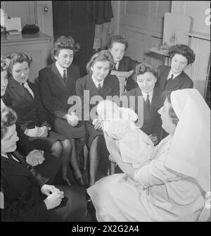 WRENS LEARN MOTHERCRAFT: I MEMBRI DEL WOMEN'S ROYAL NAVAL SERVICE RICEVONO UNA FORMAZIONE DALLA SOCIETÀ DI FORMAZIONE MOTHERCRAFT, LONDRA, INGHILTERRA, REGNO UNITO, 1945 - la Matron Miss Maslen-Jones della Mothercraft Training Society tiene un bambino appena bagnato dopo una dimostrazione al gruppo di Wrens riuniti sul modo migliore per fare il bagno a un bambino, probabilmente presso la sede centrale della MTS di Highgate Foto Stock