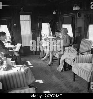 Winston Churchill viaggiò attraverso il Canada e gli Stati Uniti su un treno speciale attrezzato per il lavoro. Una fotografia lo mostra mentre legge dispacci con Clementine Churchill accanto a lui e il segretario privato John M. Martin di fronte. Foto Stock