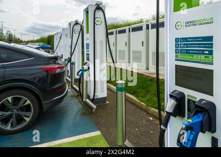 Auto presso la stazione di ricarica di veicoli elettrici, parte della rete Gridserve di punti di ricarica denominata Gridserve Electric Highway, Inghilterra Regno Unito Foto Stock