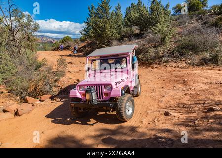 La jeep rosa della Pink Jeep Tours passa per gli escursionisti che riposano lungo la strada accidentata utilizzata dai veicoli fuoristrada a Sedona, Arizona Foto Stock