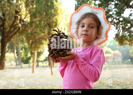 bella bambina con camicetta e cappello rosa che reggono il grande cono, concentrati sul cono Foto Stock