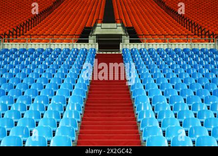 molte file di sedili in plastica rossi e blu vuoti allo stadio; scalinata Foto Stock