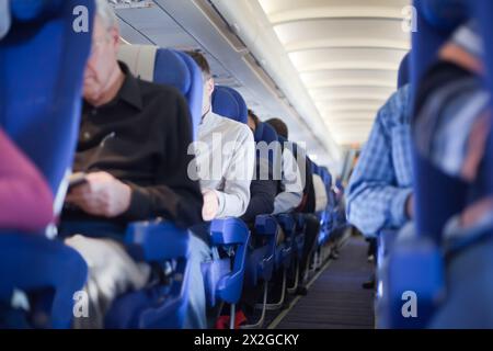 Corsia tra i sedili della cabina del velivolo, profondità di messa a fuoco bassa. Le persone sono fuori fuoco. Foto Stock