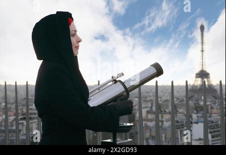 Giovane donna in piedi sull'Arco di Trionfo con un binocolo grande, Torre Eiffel Foto Stock