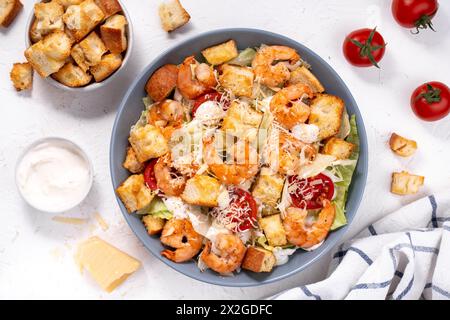 Insalata Caesar di gamberi in ciotola con parmigiano, lattuga, condimento e crostini Foto Stock