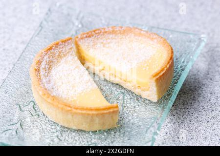 Una crostata al limone (tarte au citron) tagliata in due e spolverata con zucchero a velo Foto Stock