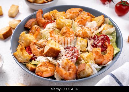 Insalata Caesar di gamberi in ciotola con parmigiano, lattuga, condimento e crostini Foto Stock