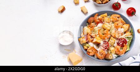 Insalata Caesar di gamberi in ciotola con parmigiano, lattuga, condimento e crostini Foto Stock