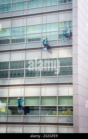 Lavavetri che lavorano in un edificio per uffici in si Lom Rd Bangkok, Thailandia. Questo è stato girato dalla passerella sopraelevata sala Daeng BTS. Foto Stock