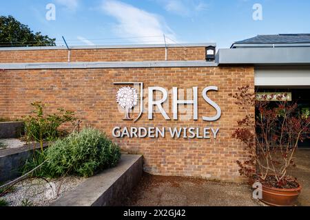 Il logo RHS e il cartello con il nome all'ingresso del RHS Garden, Wisley, Surrey, Inghilterra sud-orientale in primavera Foto Stock