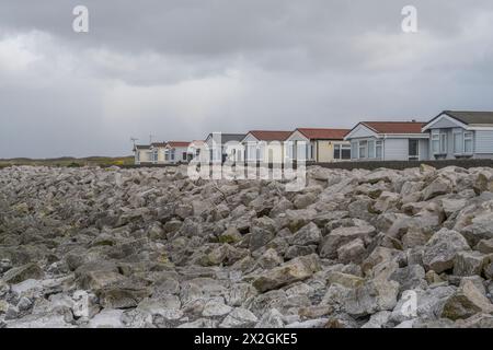 Bungalow vicino al lungomare dietro le rocce di difesa del mare, West Shore, Walney Island, Barrow-in-Furness, Cumbria, REGNO UNITO Foto Stock